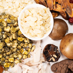A top-down flat lay of dried herbal ingredients including Siraita, South and North Almonds, Processed Black Ginger,  Candied Licorice, Baby Chrysanthemum